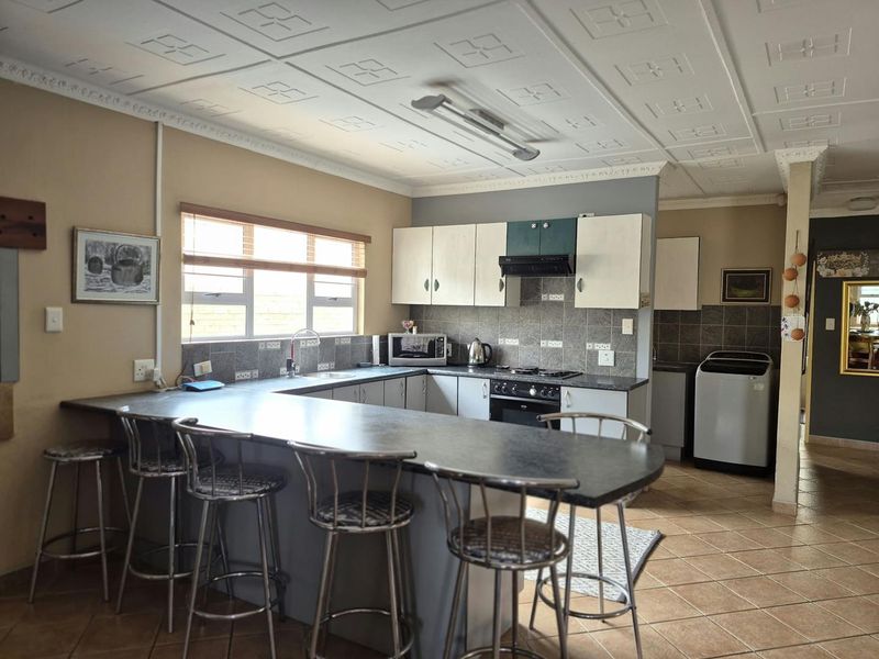 Functional kitchen featuring a u-shaped layout with a breakfast bar, built-in oven, hob, extractor fan, and tiled backsplash.