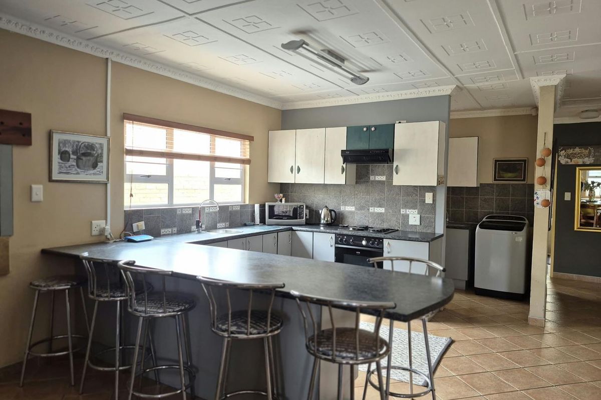 Functional kitchen featuring a u-shaped layout with a breakfast bar, built-in oven, hob, extractor fan, and tiled backsplash.