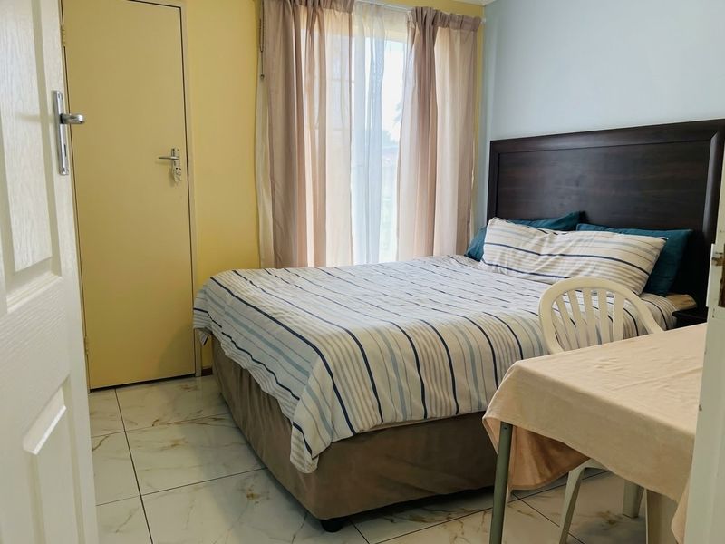 A bedroom featuring tiled flooring and a neutral color scheme, offering a functional space with natural light from the window.