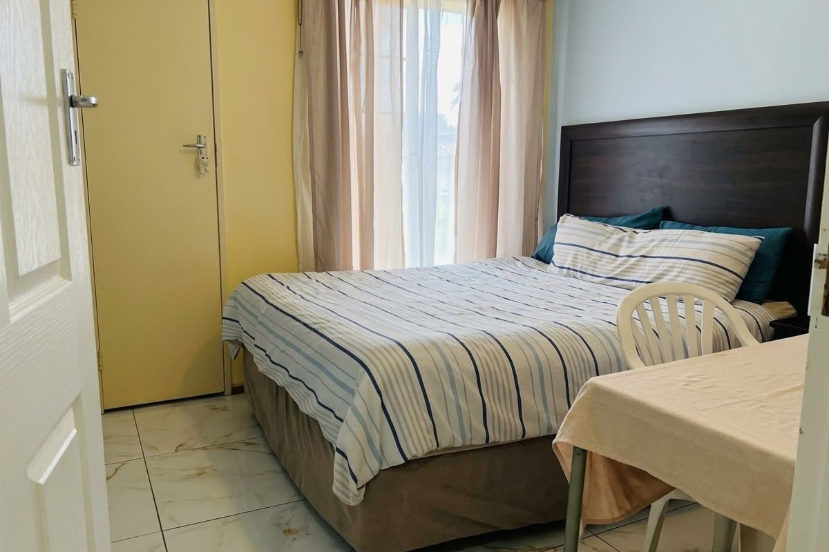 A bedroom featuring tiled flooring and a neutral color scheme, offering a functional space with natural light from the window.
