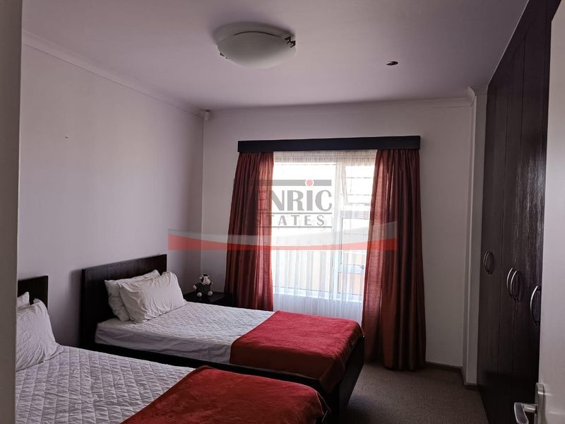 A functional bedroom featuring built-in cupboards, carpeted flooring, and a window with curtains, providing a comfortable and practical living space.