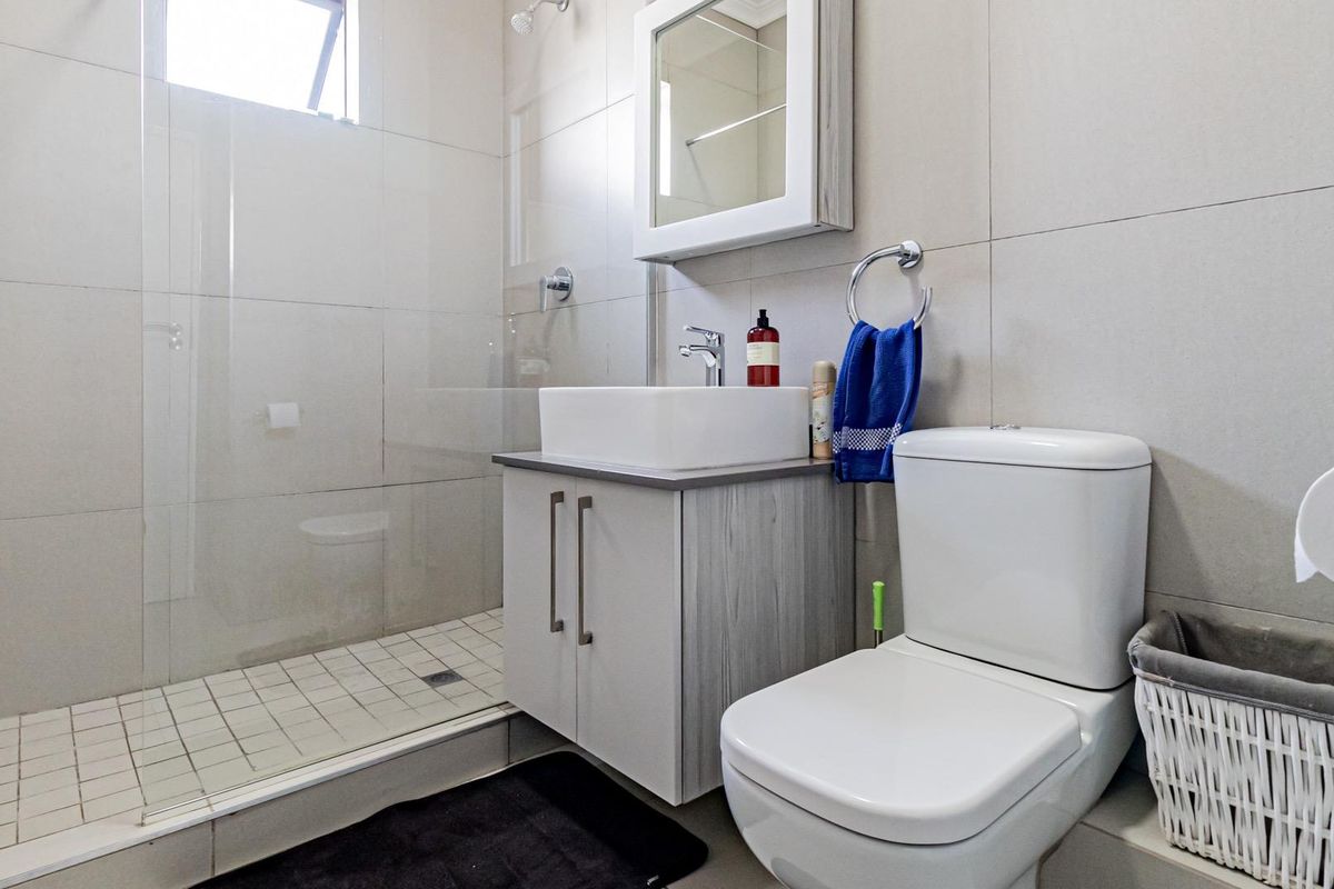 Modern bathroom featuring a walk-in shower with glass screen, vanity cabinet with vessel sink, and a wall-mounted medicine cabinet.