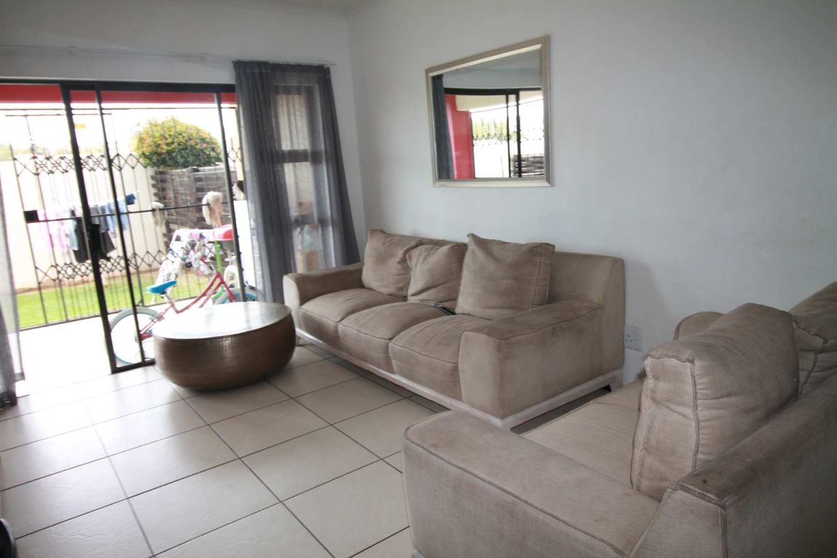 A living room featuring tiled flooring and sliding glass doors that provide direct access to an outdoor patio area.