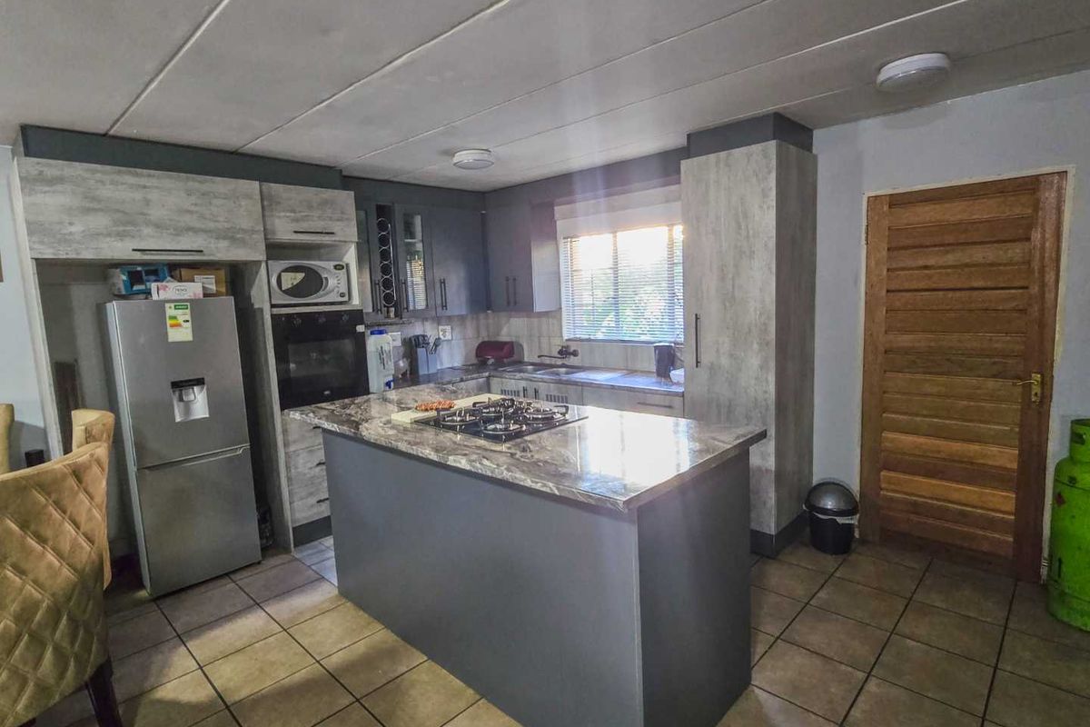 Modern kitchen featuring a central island with a gas hob, built-in oven, microwave, ample cabinetry, and tiled flooring.