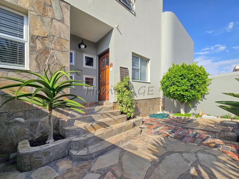 Front entrance of the house featuring stone cladding, paved steps, and a timber front door.