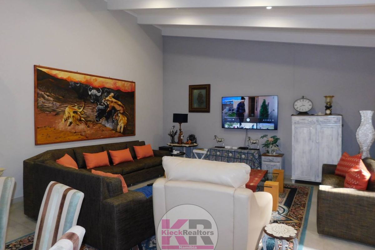 Spacious living room featuring high vaulted ceilings with exposed beams and neutral wall finishes.