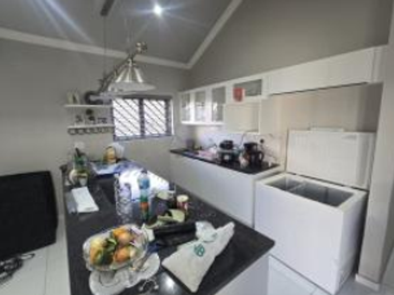 A functional kitchen featuring granite countertops, ample built-in cabinetry, and a vaulted ceiling, providing a practical workspace with good natural light.