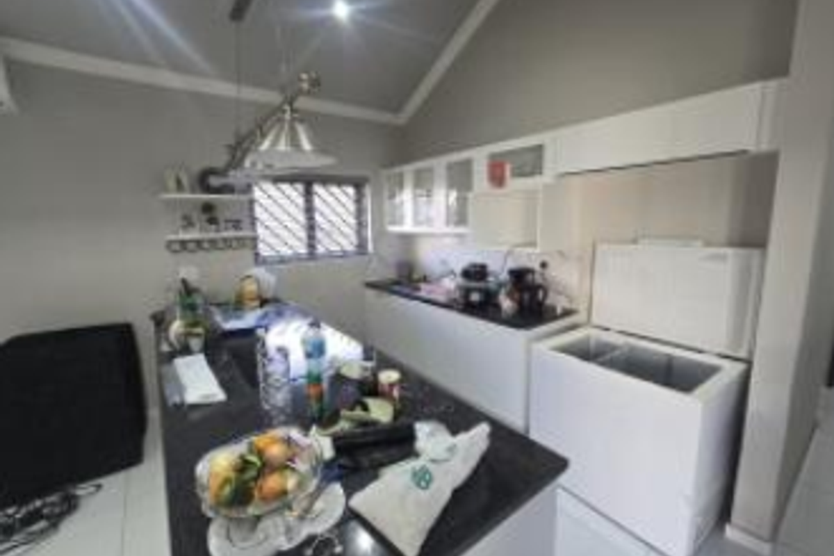 A functional kitchen featuring granite countertops, ample built-in cabinetry, and a vaulted ceiling, providing a practical workspace with good natural light.