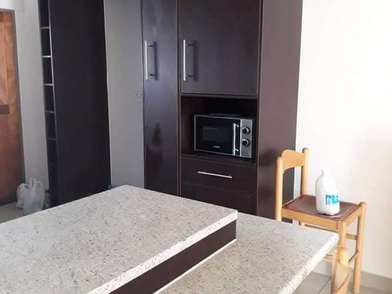 A kitchen area featuring dark wood built-in cabinetry, a stone-topped island or breakfast bar, and tiled flooring.