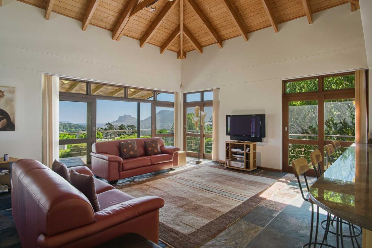 Spacious living area featuring a vaulted timber ceiling, slate flooring, and expansive glass doors offering scenic mountain views and abundant natural light.