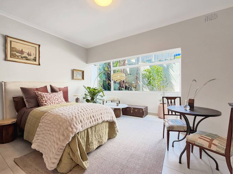 A bright and spacious bedroom featuring large windows that provide natural light and a pleasant outlook.