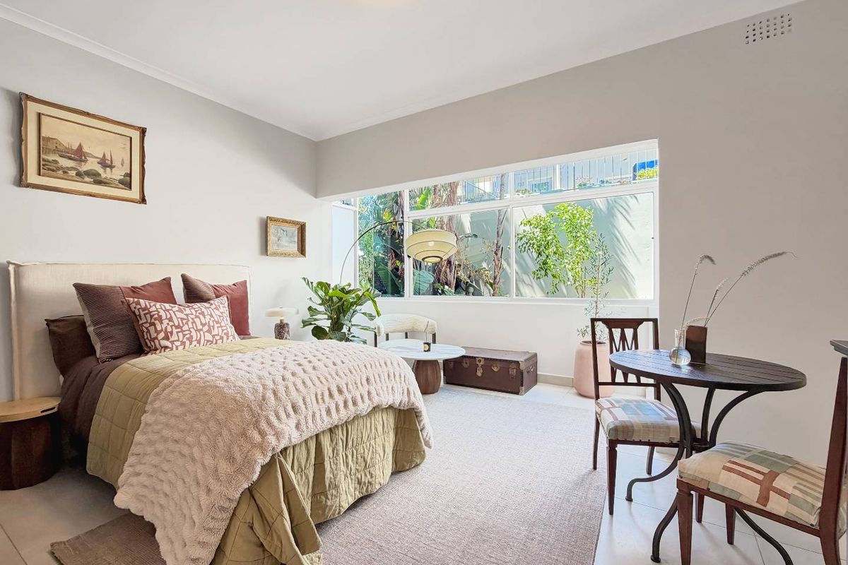 A bright and spacious bedroom featuring large windows that provide natural light and a pleasant outlook.