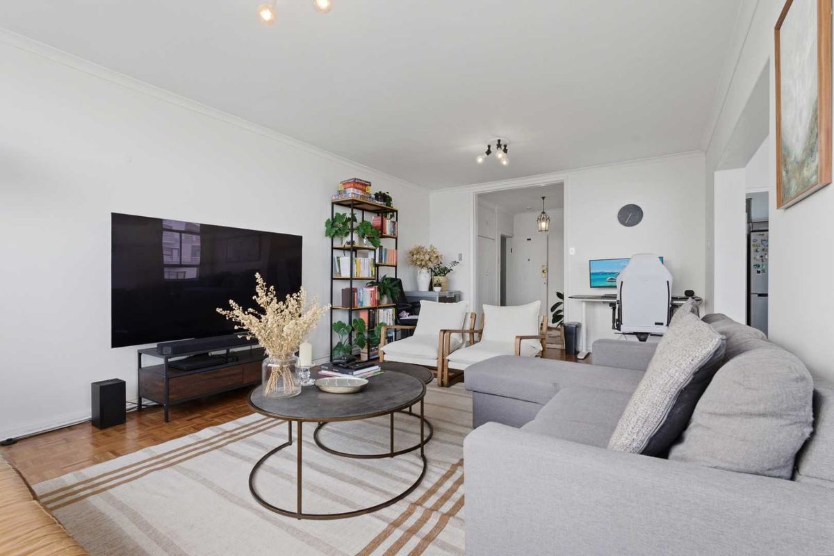 A well-maintained living room featuring classic parquet flooring, neutral walls, and cove cornicing, providing a comfortable and inviting space.
