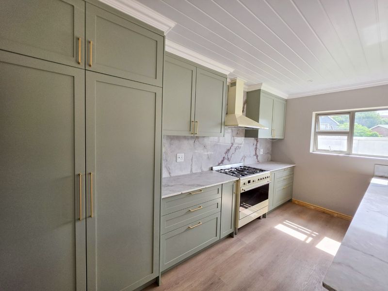Modern kitchen featuring sage green shaker-style cabinetry, marble-look countertops and backsplash, gas hob, and integrated oven, finished with a tongue and groove ceiling.