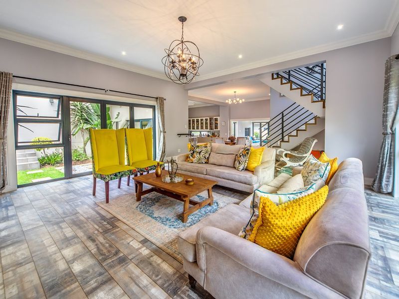 Spacious open-plan living area featuring modern tiled flooring, a feature staircase with metal balustrades, and large aluminium sliding doors leading to the garden.