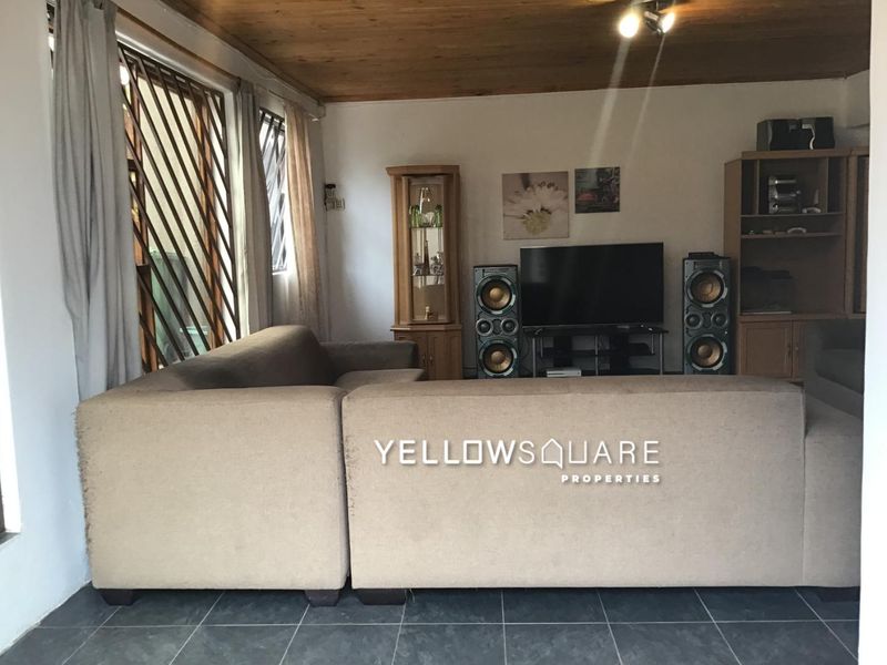 A living room featuring a timber ceiling, tiled flooring, and security bars on the windows.