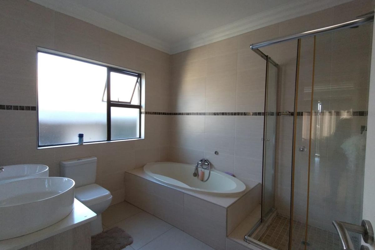 A well-appointed bathroom featuring a built-in bathtub, a separate glass-enclosed shower, and dual vessel sinks on a vanity unit.