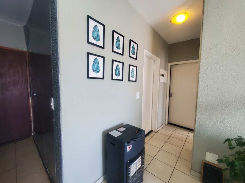 A functional apartment hallway featuring neutral wall tones and tiled flooring, providing access to multiple rooms within the residence.