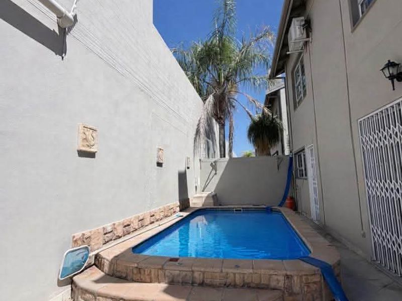 A private outdoor pool area featuring stone-clad steps, tiled patio flooring, and direct access to the townhouse exterior.
