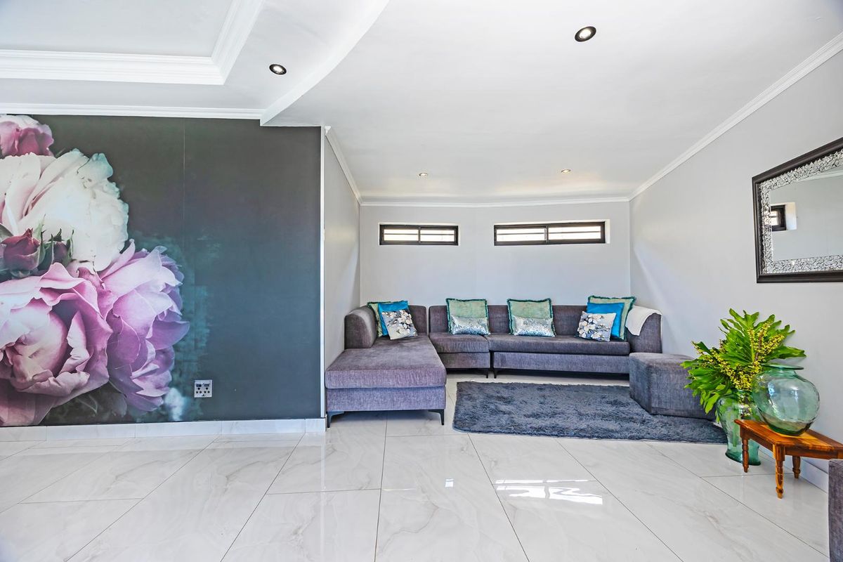 A modern living room featuring polished porcelain floor tiles, a coved ceiling with recessed lighting, and horizontal clerestory windows.