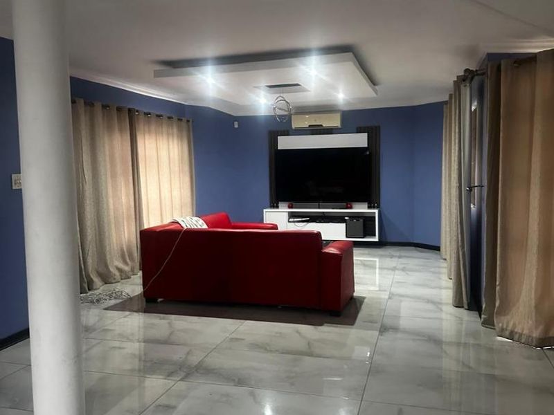 Spacious living room featuring polished marble-look floor tiles, a recessed ceiling with downlights, and a wall-mounted air conditioning unit.
