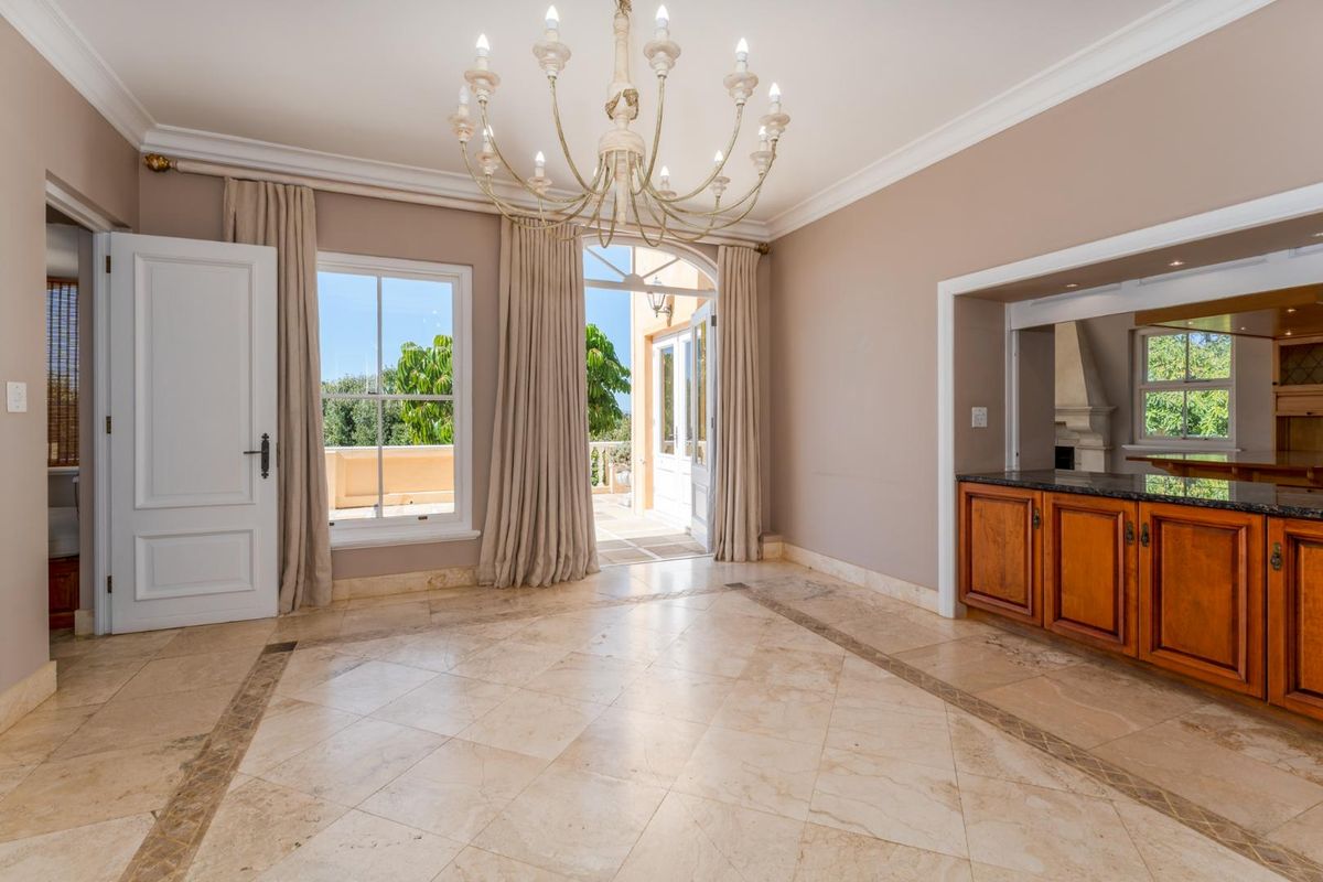 Spacious living area featuring elegant marble flooring, a classic chandelier, and direct access to an outdoor patio through arched glass doors.