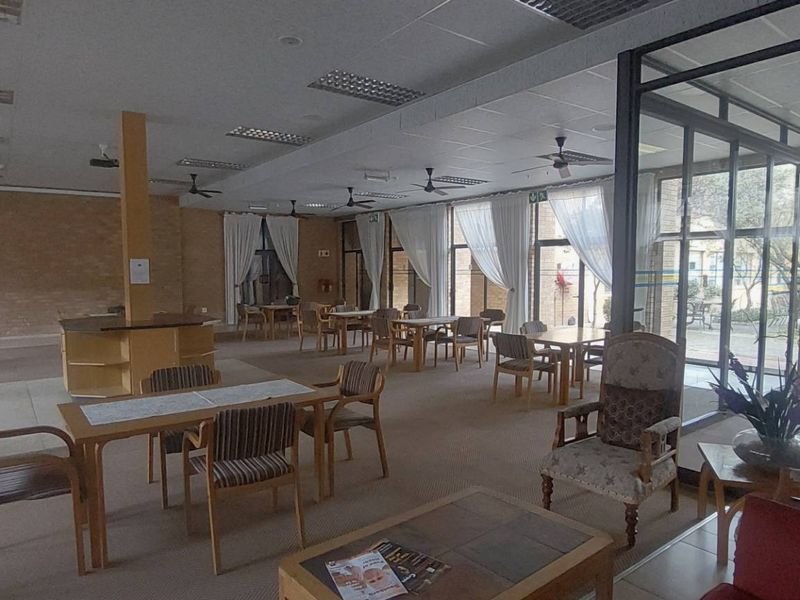 Spacious communal clubhouse area featuring exposed brick walls, large glass partitions, and ample natural light, suitable for social gatherings and resident activities.