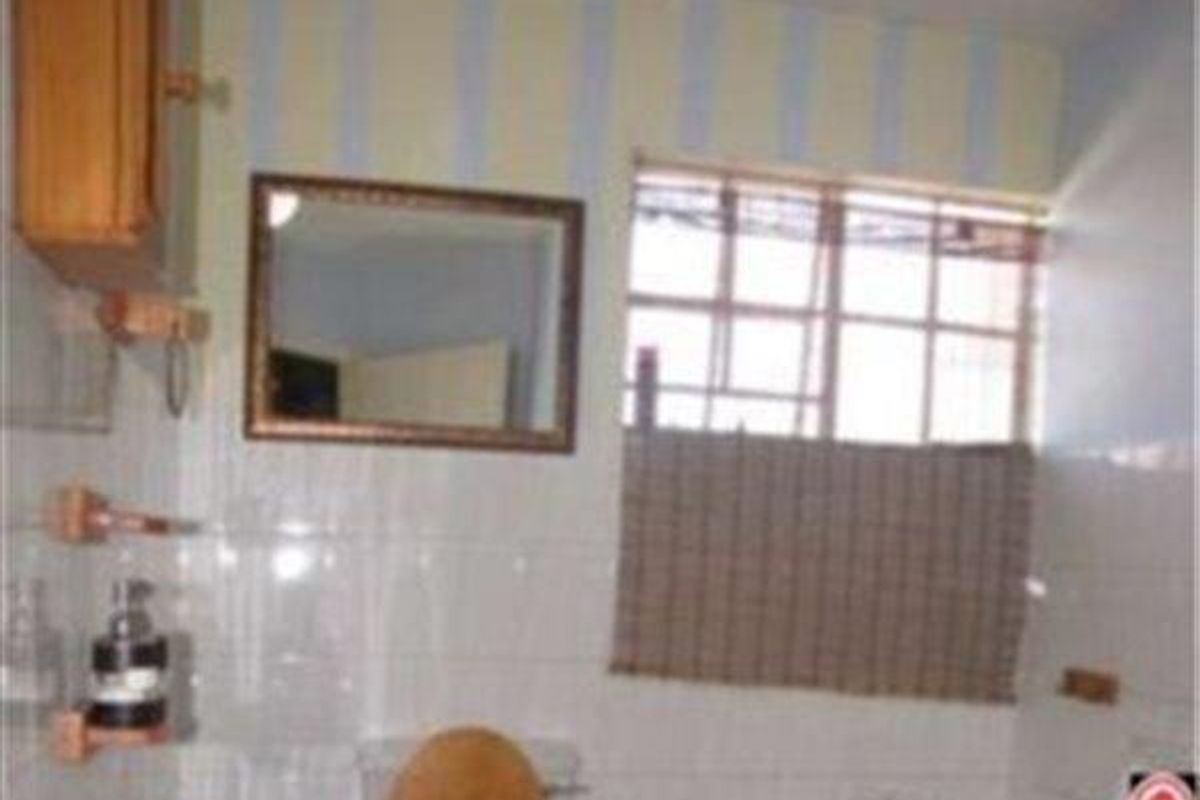 A dated bathroom featuring tiled walls, a wall-mounted mirror, and a window, offering potential for modernization and renovation.