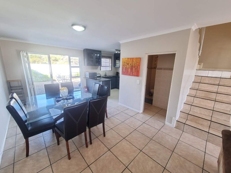 Open-plan living and dining area featuring tiled floors, a staircase, and direct access to the kitchen and a ground-floor guest toilet.