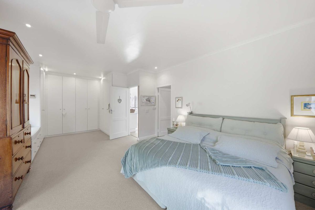 Spacious bedroom featuring extensive built-in cabinetry, neutral carpeting, recessed lighting, and a ceiling fan, offering a clean and well-maintained living space.