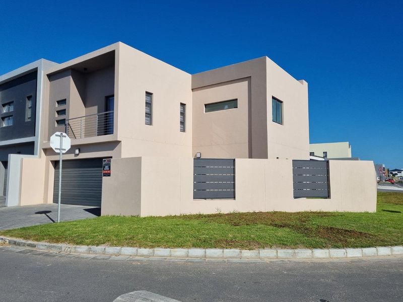Modern double-storey home featuring a clean facade, automated garage, balcony with metal railings, and a secure boundary wall with integrated slat panels.