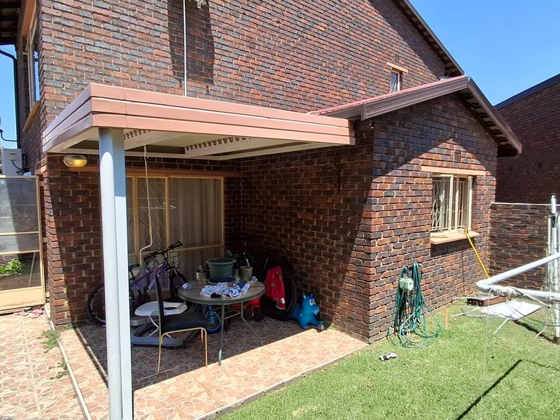 A covered brick patio area featuring tiled flooring and direct access to the interior through a sliding glass door.