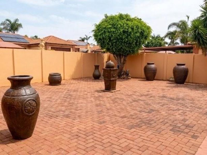 A spacious rear courtyard featuring extensive brick paving, a high boundary wall for privacy, and established landscaping.