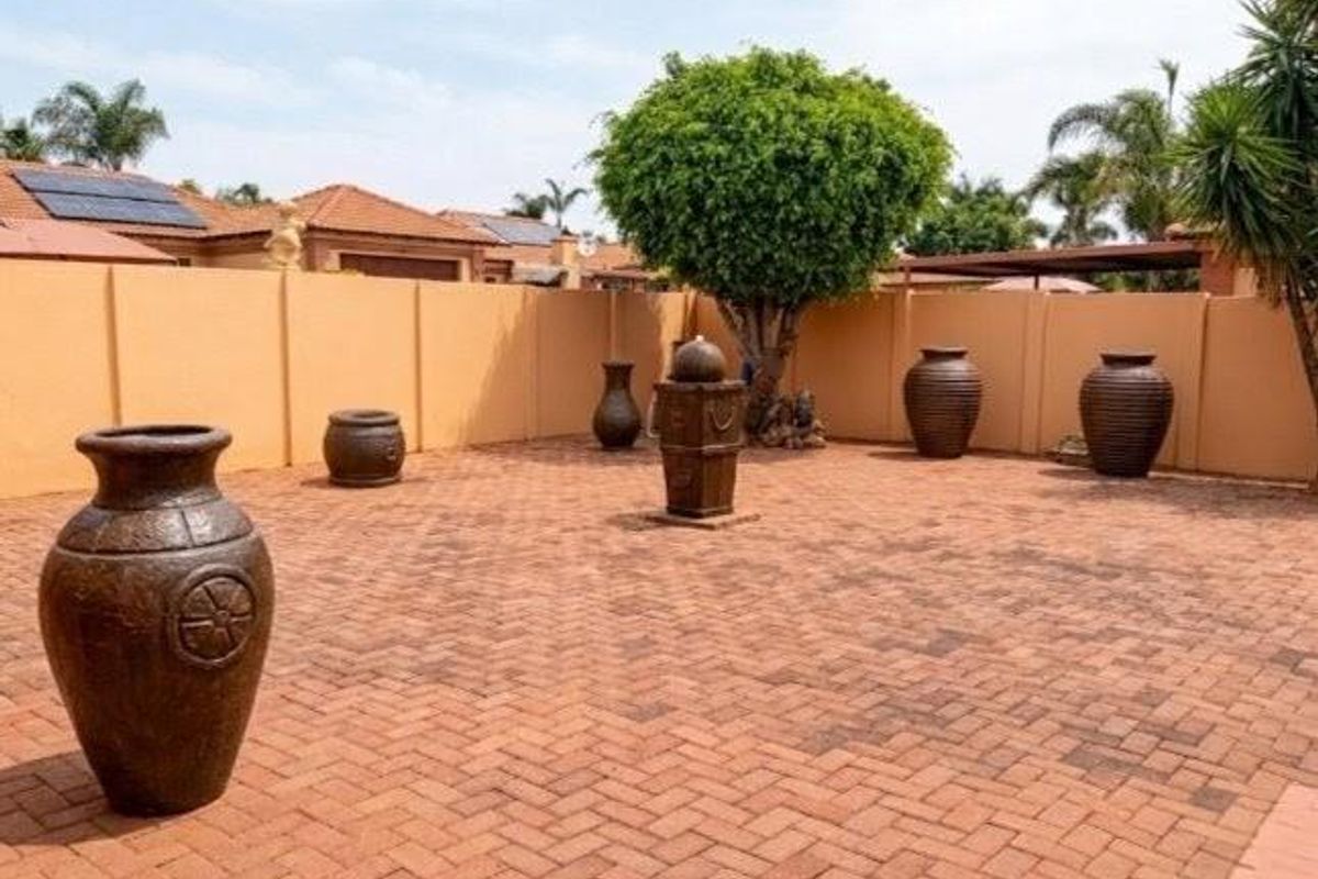 A spacious rear courtyard featuring extensive brick paving, a high boundary wall for privacy, and established landscaping.