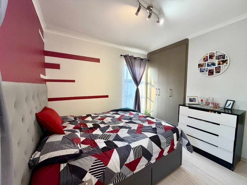 A well-maintained bedroom featuring a built-in wardrobe, modern track lighting, and neutral flooring, offering a functional and comfortable living space.