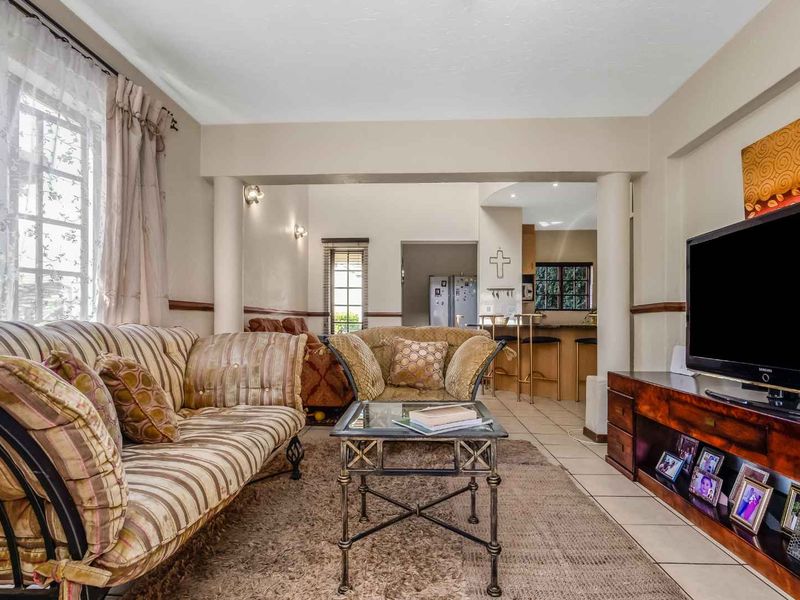 Open plan living area featuring ceramic floor tiles, structural columns, and a breakfast bar connecting to the kitchen space.