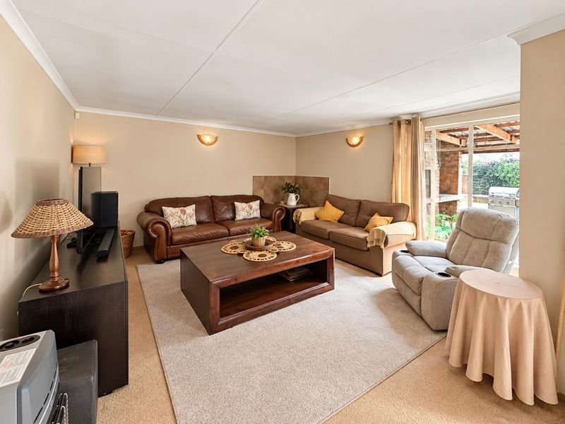 A comfortable living room featuring neutral walls, coved ceilings, and a sliding glass door providing access to the outdoor patio area.
