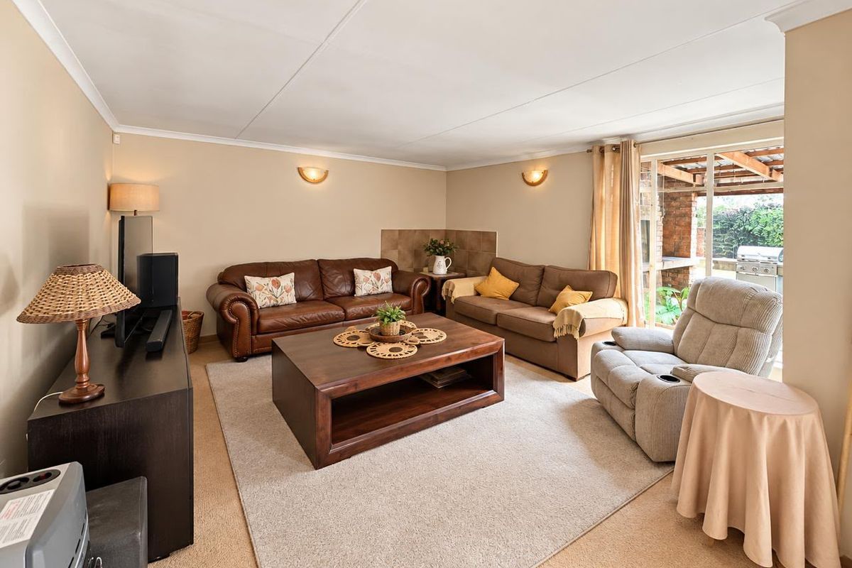 A comfortable living room featuring neutral walls, coved ceilings, and a sliding glass door providing access to the outdoor patio area.