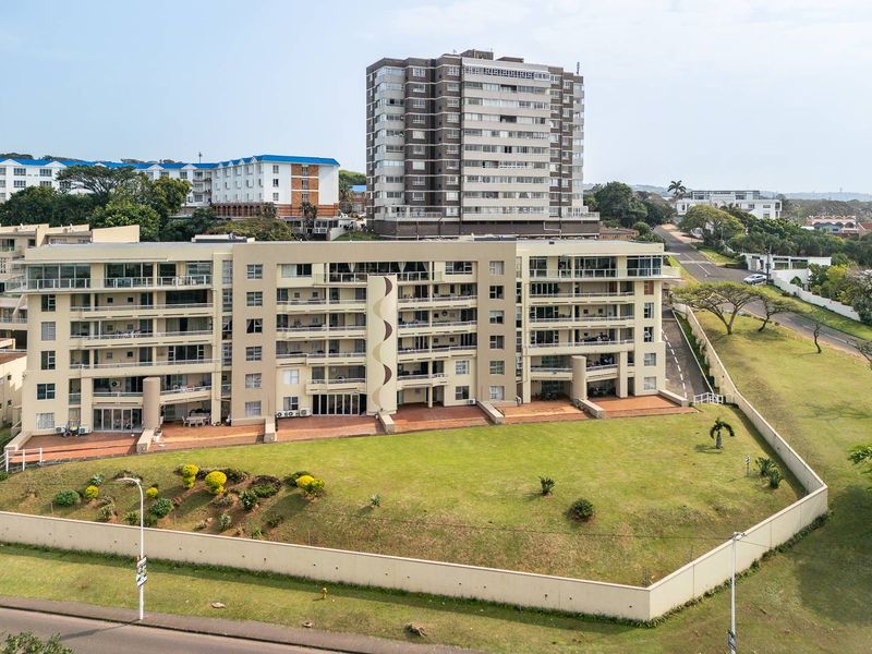 Aerial view of a multi-story townhouse complex featuring private balconies, paved patio areas, and surrounding landscaped grounds within a residential neighborhood.
