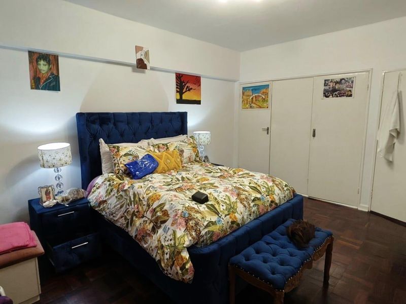 A bedroom featuring parquet flooring and built-in cupboards, providing functional storage space.