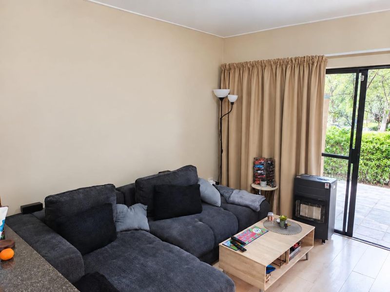 A living room area featuring laminate flooring and a sliding glass door providing access to an outdoor space.