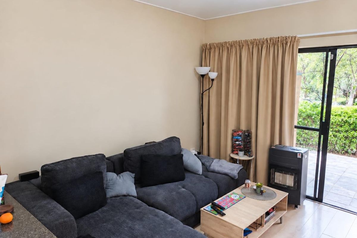 A living room area featuring laminate flooring and a sliding glass door providing access to an outdoor space.