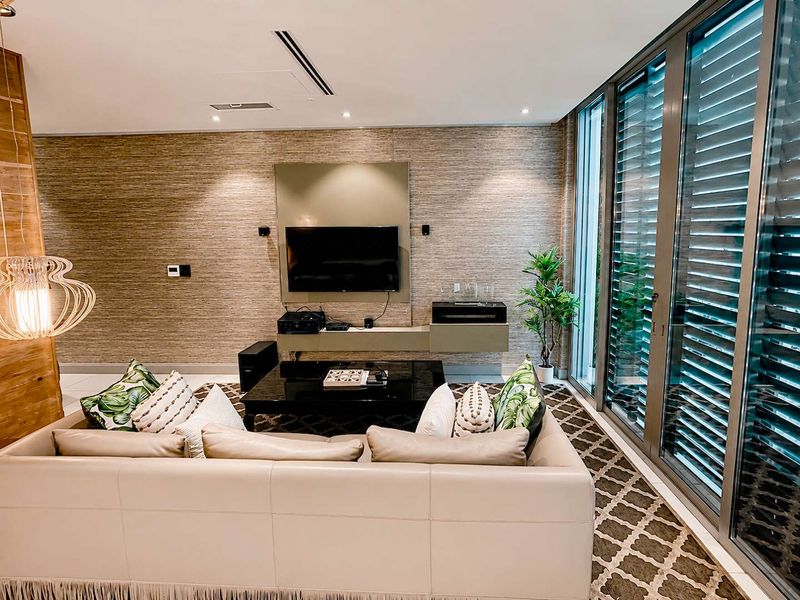 Modern living room featuring textured wall finishes, built-in media cabinetry, recessed lighting, and large sliding glass doors providing ample natural light.