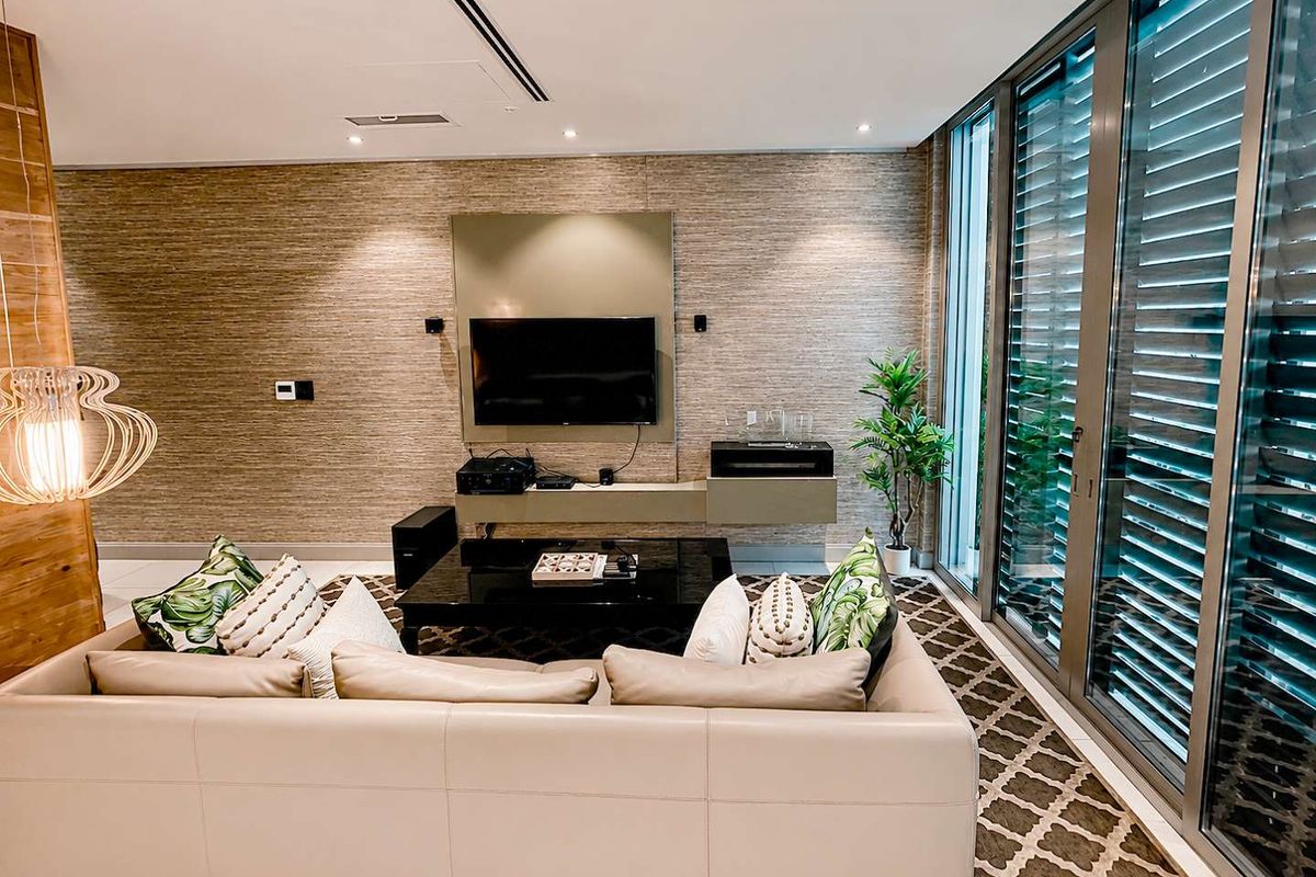Modern living room featuring textured wall finishes, built-in media cabinetry, recessed lighting, and large sliding glass doors providing ample natural light.