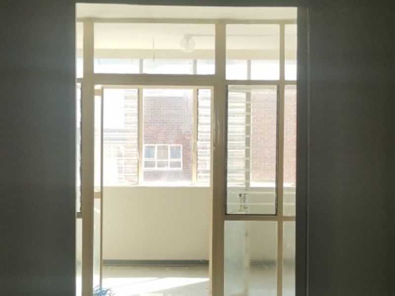 An enclosed balcony area featuring tiled flooring and aluminum window frames, offering a bright and versatile space for potential use.