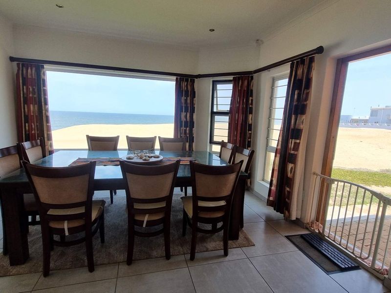 Bright dining room featuring large windows with direct ocean views and seamless access to the outdoor patio area.