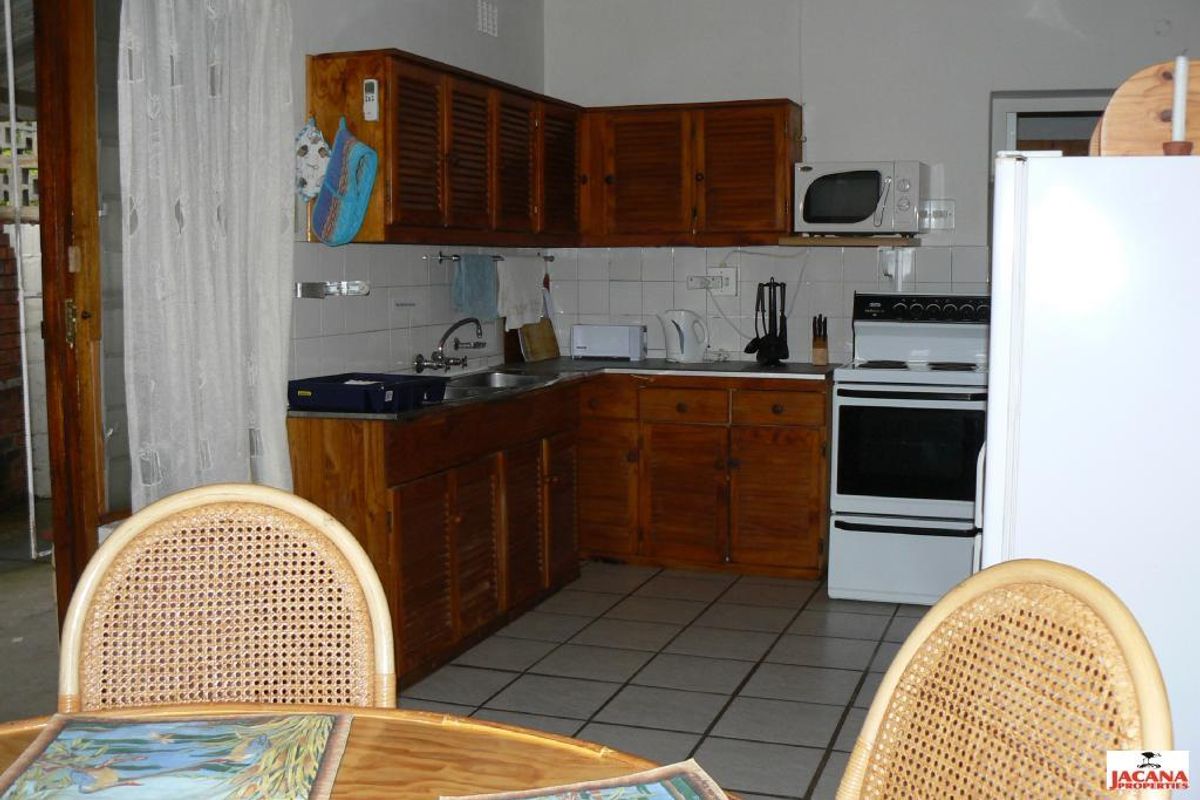 A dated kitchen featuring wooden cabinetry, tiled splashbacks, and a freestanding stove, offering a functional layout with potential for modernization.