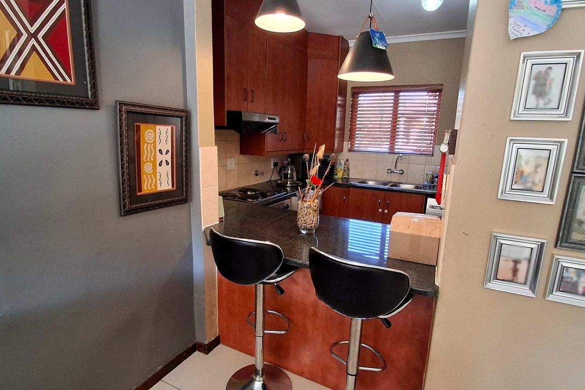 Compact kitchen featuring wooden cabinetry, granite countertops, a breakfast bar, and integrated appliances, offering a functional layout for daily use.