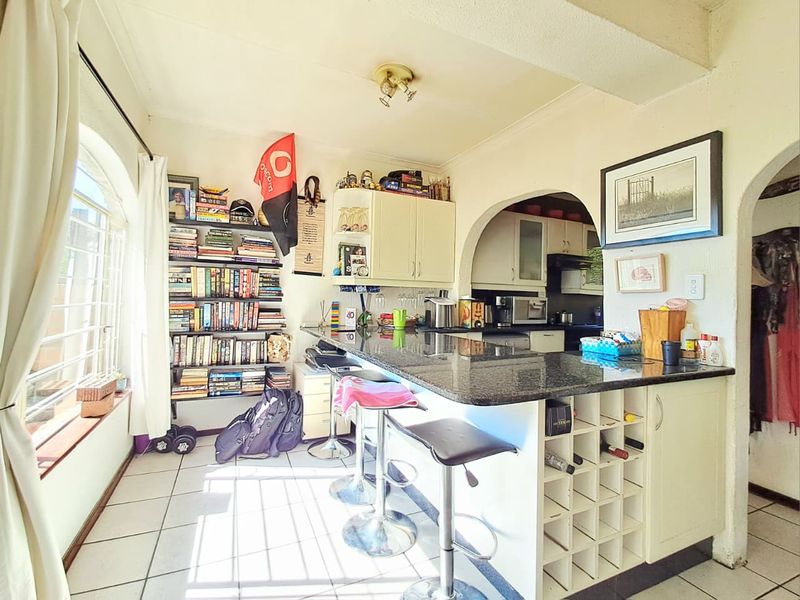 Open-plan living and kitchen area featuring a granite breakfast bar, built-in wine storage, and arched architectural details with tiled flooring throughout.