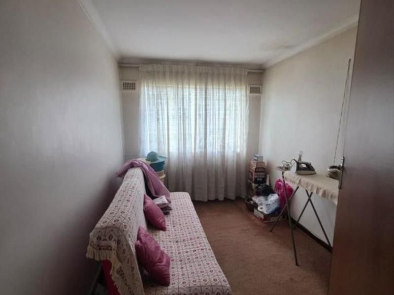 A compact bedroom featuring carpeted flooring, neutral walls, and a window with installed curtain rails.